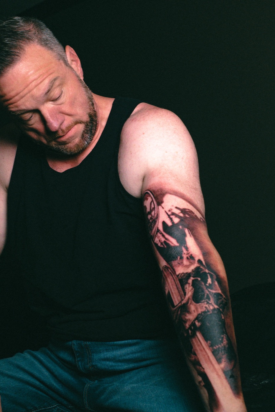 The client looking down at the finished skull and blade on his forearm