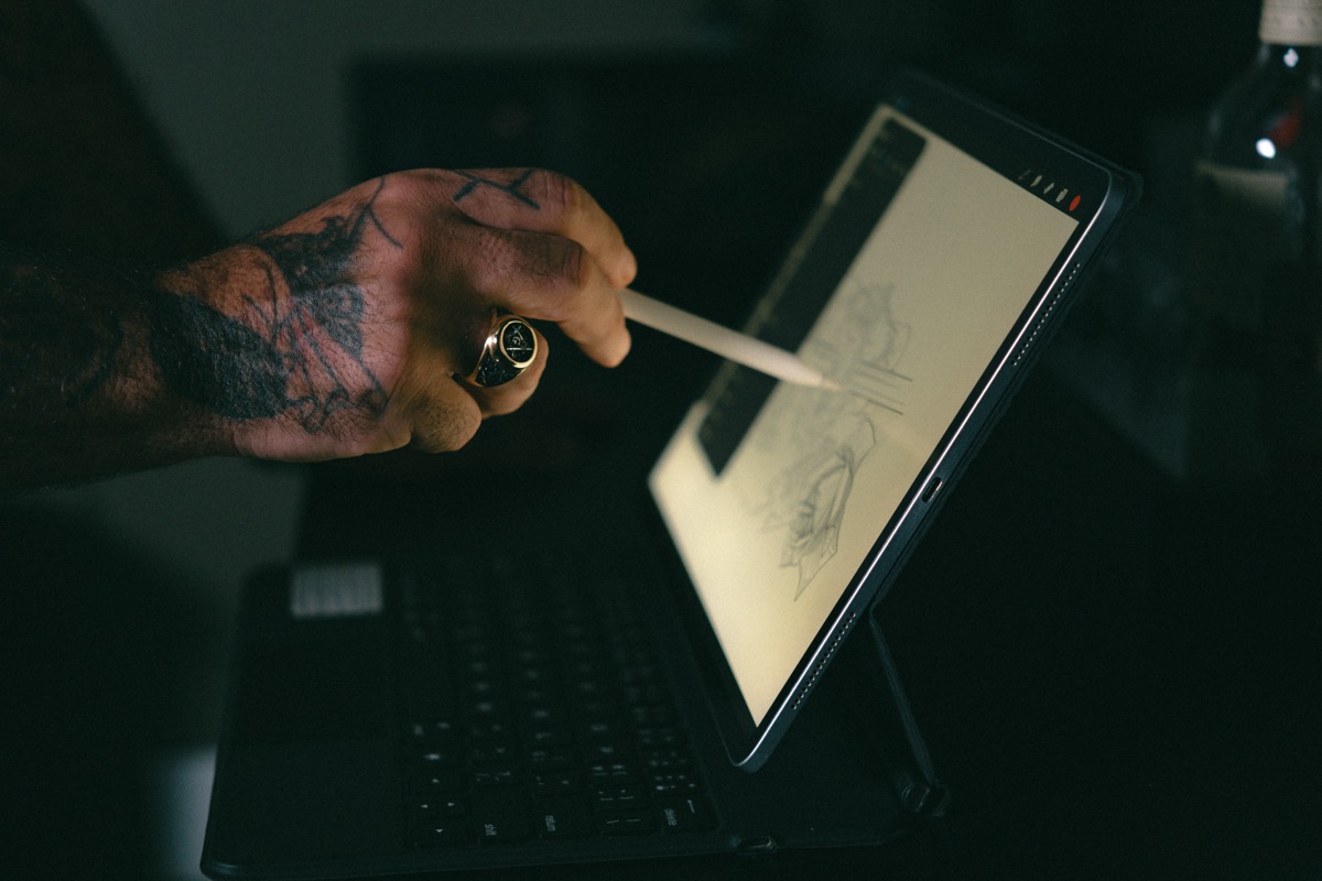 The skull and blade being drawn by hand on a tablet screen in the dark