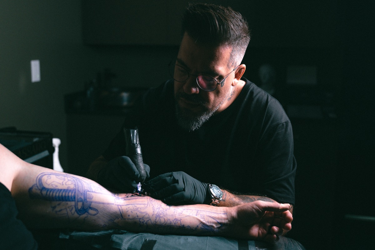 The first pass of the machine over the blue stencil on the forearm