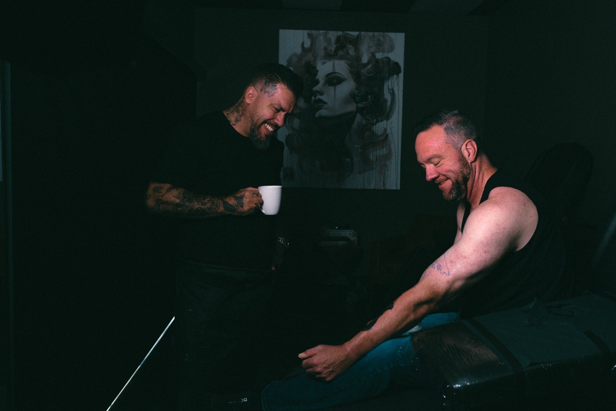 Rafael Cassaro and the client laughing between passes, coffee in hand