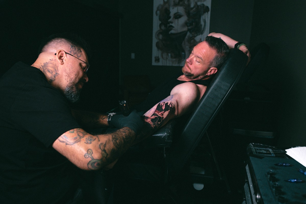 The session seen wide, the client resting back while the arm is worked