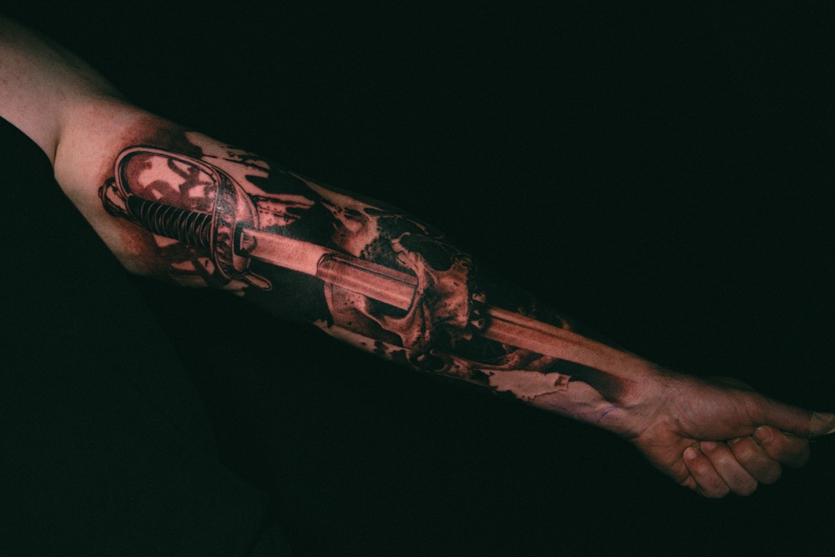The finished skull and blade in black and grey, running the length of the forearm